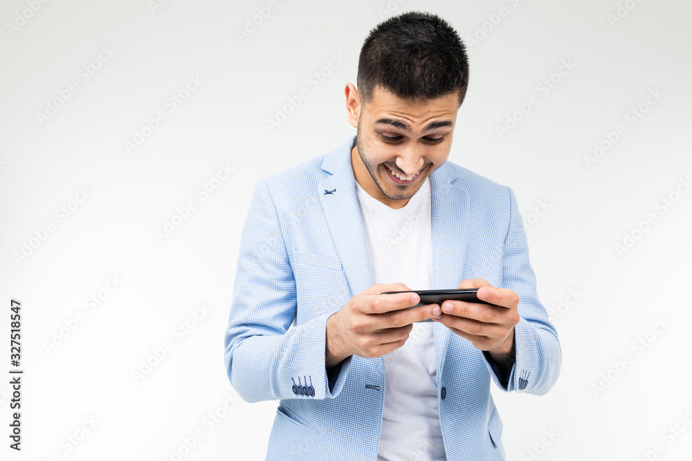 portrait of a happy man in a blue jacket playing a game on a smartphone in a horizontal position portrait of a happy man in a blue jacket playing a game on a smartphone in a horizontal position