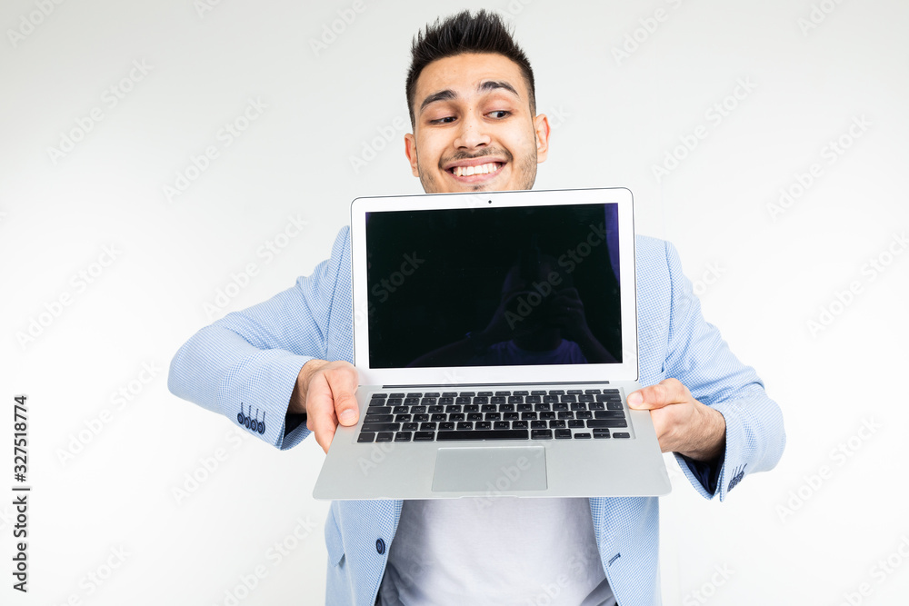 smiling young brunette man holding a laptop screen to the camera with a blank mockup on a white background smiling young brunette man holding a laptop screen to the camera with a blank mockup on a white background