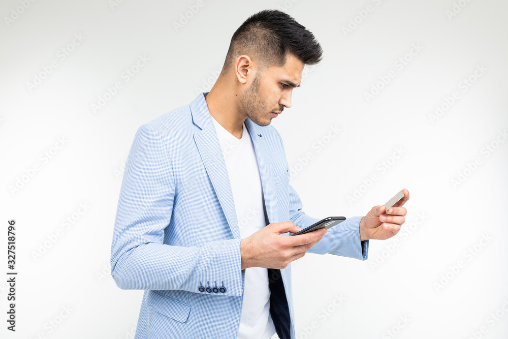 handsome man orders online purchases from a smartphone holding a credit card in his hands handsome man orders online purchases from a smartphone holding a credit card in his hands
