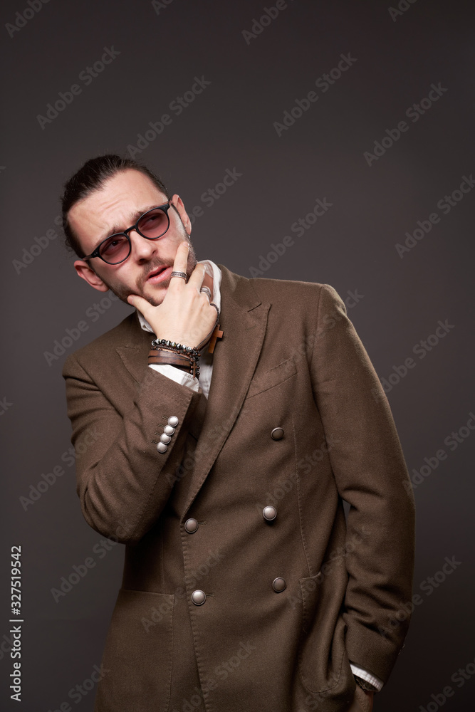 Fototapeta premium Pensive guy with beard in jacket on blank brown background