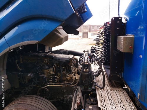 Space between truck cab and trailer. Folded tractor connected with hoses and connections.Tilted blue  cab tractor and attached blue trailer. A revision or repair is required.
