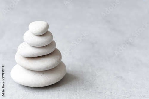 Stack of white pebbles on a neutral light grey background as balance and wellness concept photo