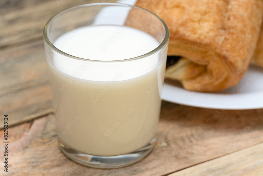 Glass of milk, rolls, sliced loaf on a wooden background Glass of milk, rolls, sliced loaf on a wooden background