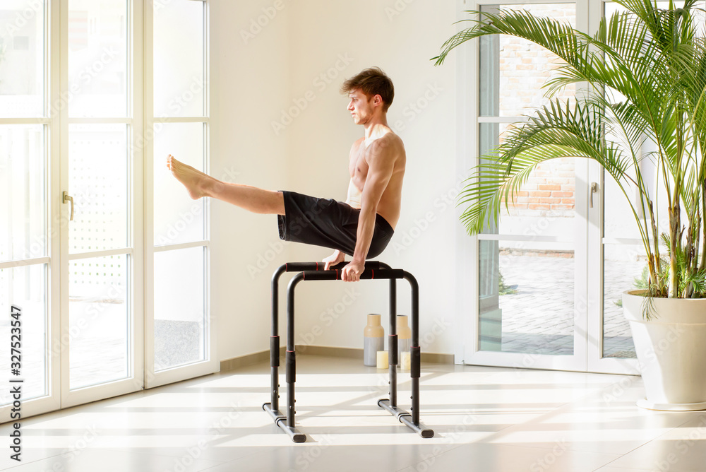 Fototapeta premium Fit young man working out on parallel bars