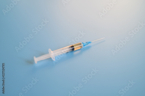 syringe with injection vaccine on a blue background. medicine plastic disposable vaccination equipment. coronavirus vaccination concept. flare