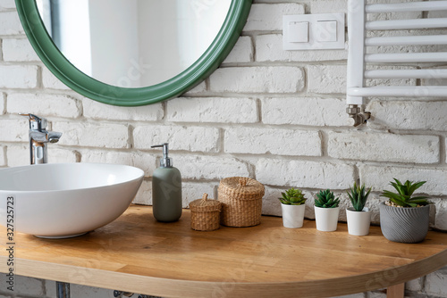 Interior of bathroom with modern design. White bricks,design basin and wooden counter with cactus. Bright indoor in industrial style and modern architecture. photo