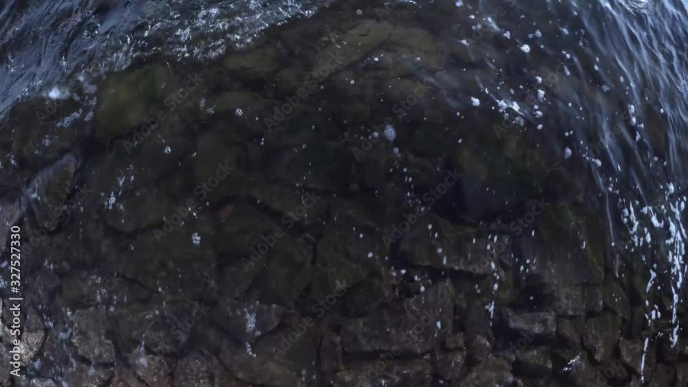 dark background the water of the river shimmers in the light, waves beat on the rocks dark background the water of the river shimmers in the light, waves beat on the rocks