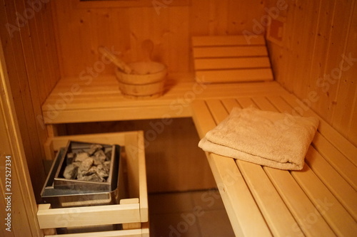 Inside a small wooden house sauna with heated rocks and bucke