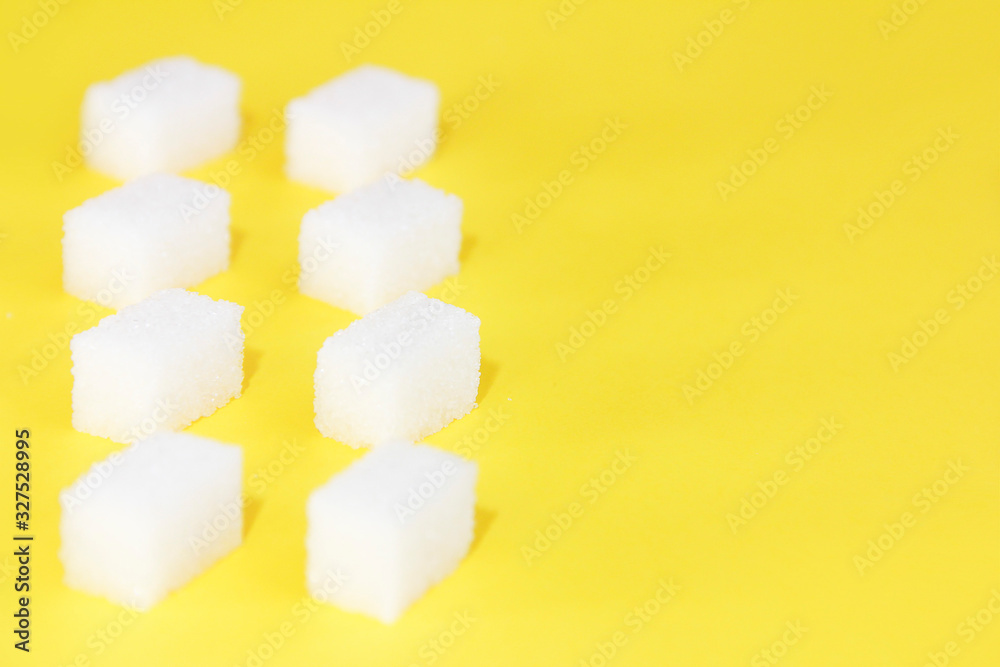 small pieces of natural white refined sugar on a yellow background small pieces of natural white refined sugar on a yellow background