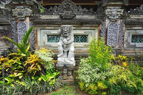 Carved stone warrior statue among tropical foliage outside ancient temple in Bali Indonesia photo