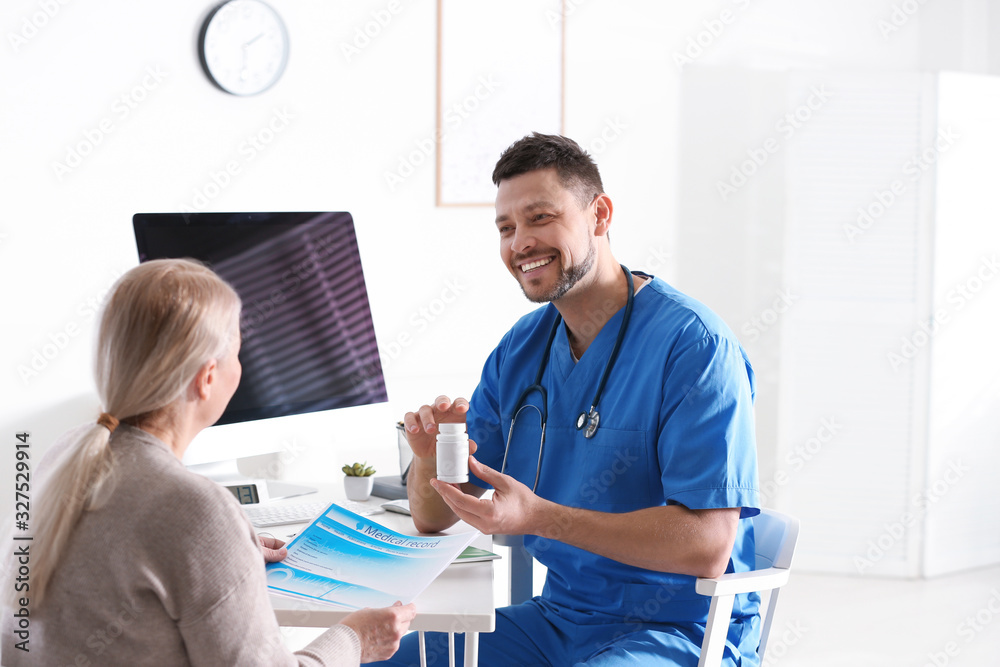 Fototapeta premium Doctor consulting patient at desk in clinic