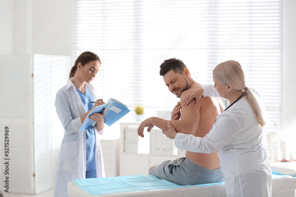 Female orthopedist examining patient's arm in clinic Female orthopedist examining patient's arm in clinic
