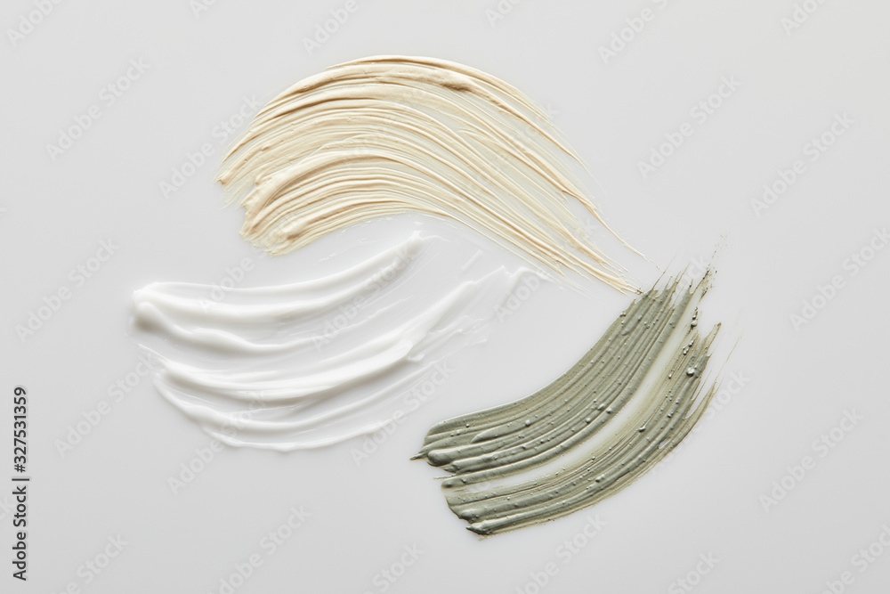 Top view of clay, cosmetic and tone cream brushstrokes on grey background Top view of clay, cosmetic and tone cream brushstrokes on grey background