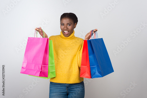 Beautiful African American woman showing shopping bags. Attractive smiling young lady with paper bags looking at camera. Shopping concept