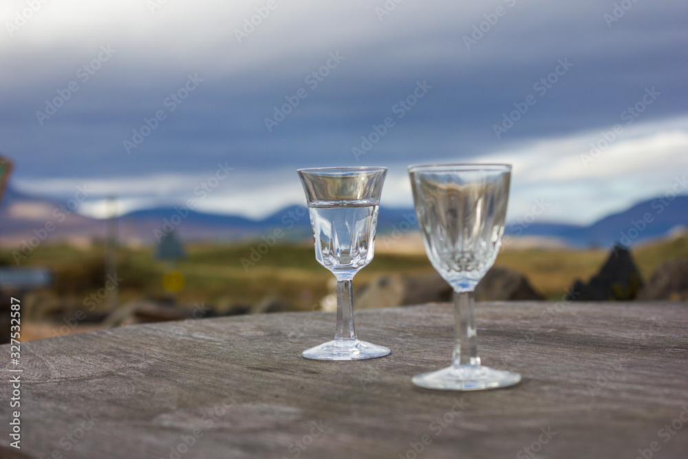 small transparent glass cups filled with water on wooden surface, blurred background small transparent glass cups filled with water on wooden surface, blurred background