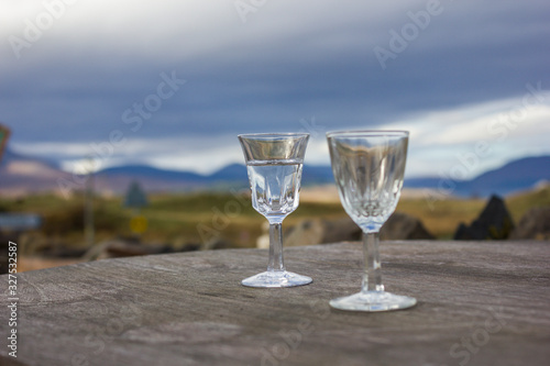 small transparent glass cups filled with water on wooden surface, blurred background