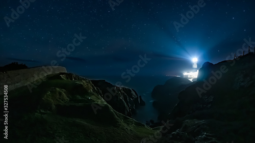 Beams of light shining from Fanad Head Lighthouse at dark night with sky full of stars. Long exposure photography. Wild Atlantic Way, Donegal, Ireland photo