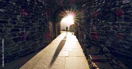 View on a woman from behind during the sunset  between stone passage in the Scottish ruins.