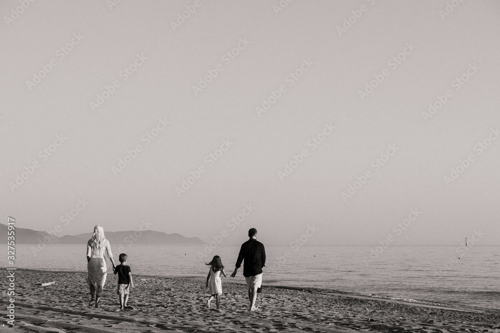 black and white photo of a family near the sea on the beach  a background of mountains