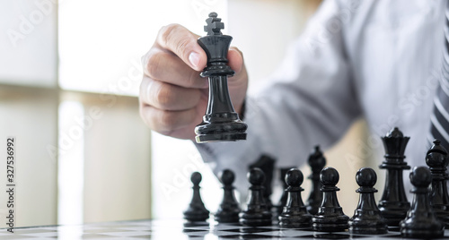 Black and White chess with player, Hands of businessman thinking to moving chess figure in competition and planning strategy to success play for win