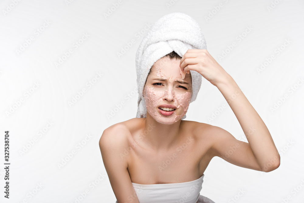 displeased girl removing peeling mask from face while looking at camera isolated on white displeased girl removing peeling mask from face while looking at camera isolated on white