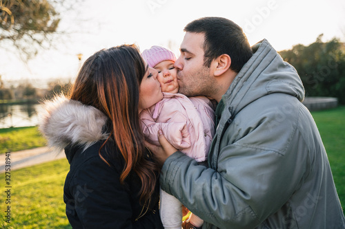 Happy family at the park - Mom and dad with their child in a park at sunset - Mother and father with their daughter in a moment of intimacy and fun © loreanto