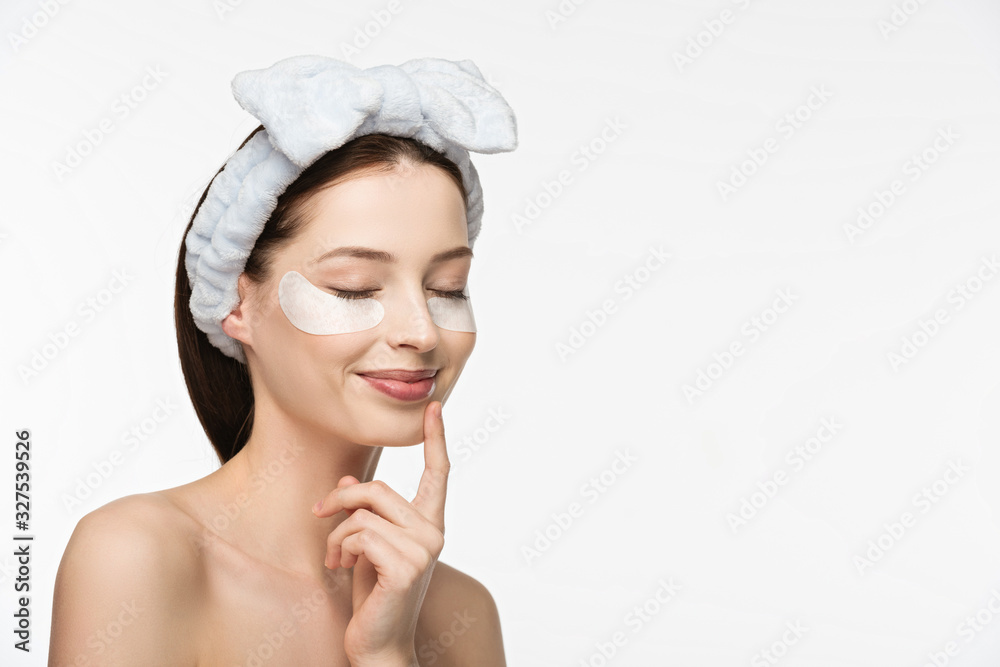 dreamy, smiling girl with eye patches touching chin with closed eyes isolated on white dreamy, smiling girl with eye patches touching chin with closed eyes isolated on white