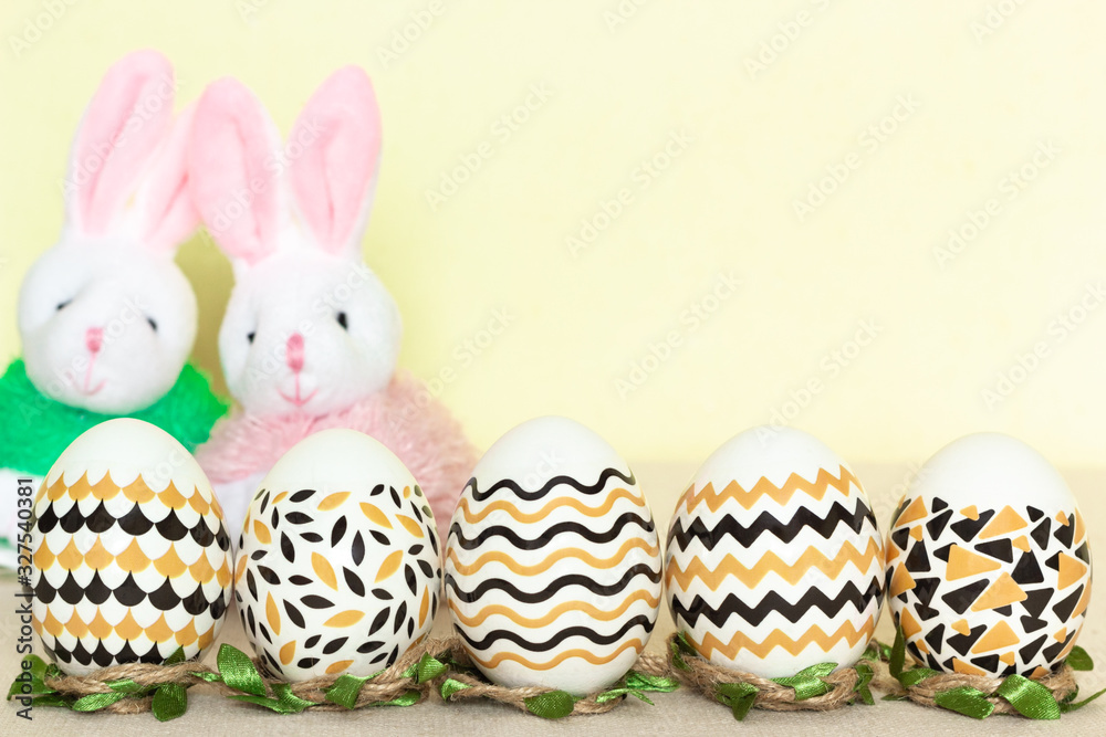 Close up eggs decorated yellow black pattern with yellow background and two toy rabbits. Easter concept with copy spase Close up eggs decorated yellow black pattern with yellow background and two toy rabbits. Easter concept with copy spase