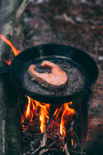 A piece of salmon in a pan over a fire. Cooking in nature. Grilled fish.
