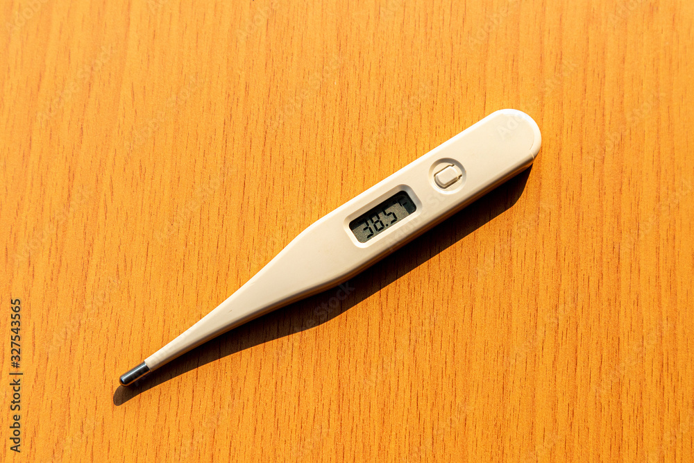 A digital thermometer on a wooden table. A digital thermometer on a wooden table.