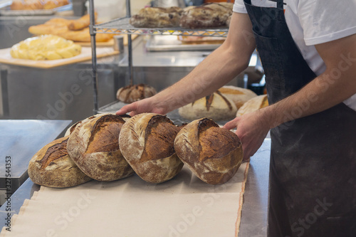 Baker in a bakery with bread and oven in the background. Industry