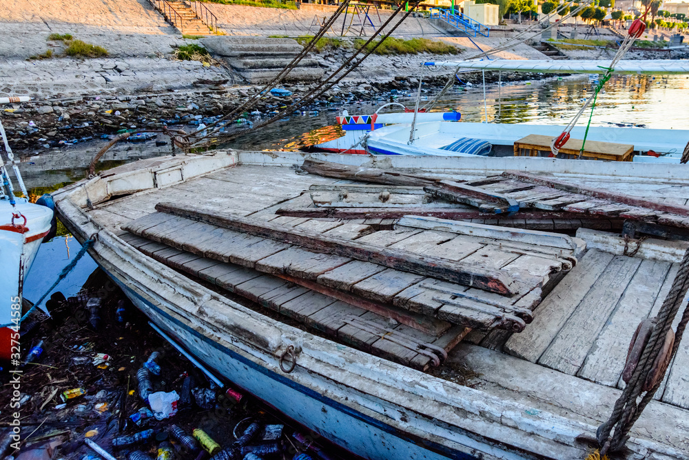 Old boats moored in a dirty harbour. Pollution of river, sea, ocean water with plastics and other garbage. Environmental pollution concept