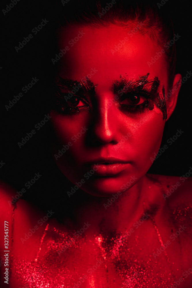 Studio portrait of a girl in red light on a black background Studio portrait of a girl in red light on a black background