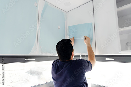 removal of a protective film,protective film,man removes kitchen protective film,new white kitchen sealed in protective film,hands of man removing protective glass