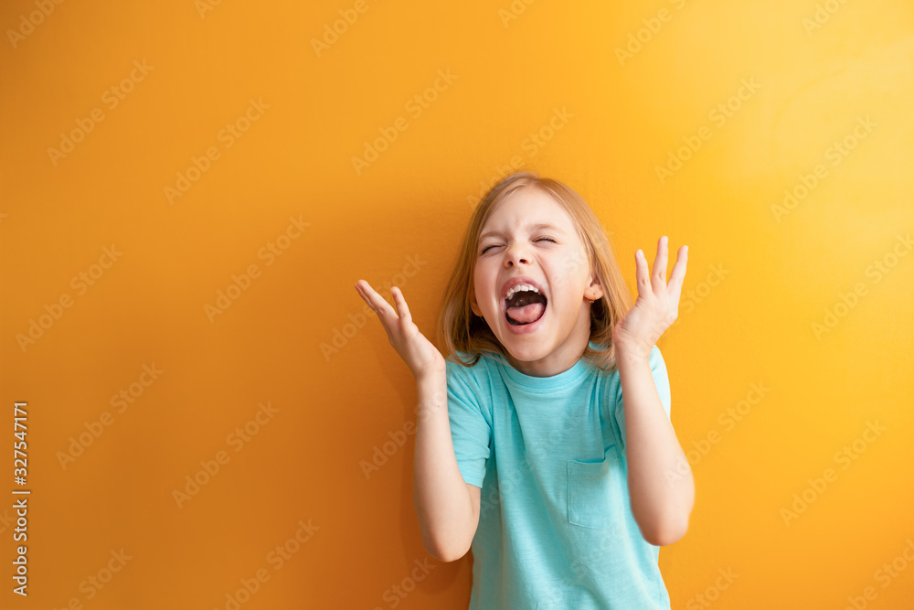 Indignant Children cute child on an orange background, 6-8 years old, girl screams ...
