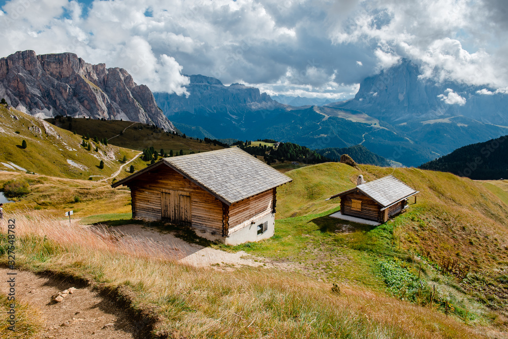 Landscape with small wooden houses on the background of the Alpine mountains. Hike to the tops of Seceda. Sunny landscape in South Tyrol