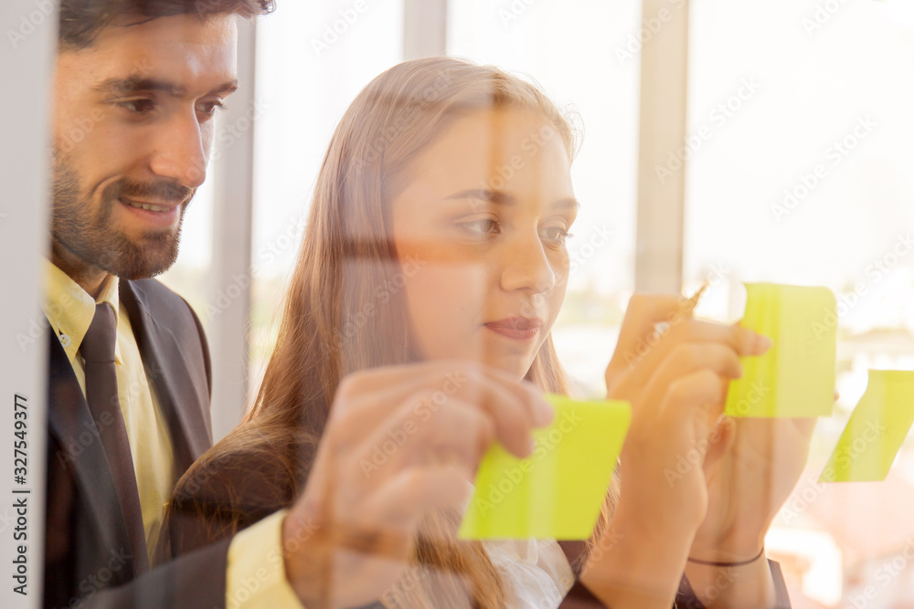 Two business men and women put notes on clear glass and have a beautiful orange light. Two business men and women put notes on clear glass and have a beautiful orange light.