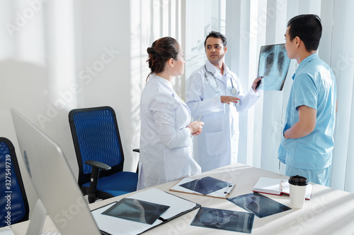 Doctor showing chest x-ray of patient with dangerous virus to coworkers and discussing threatment photo