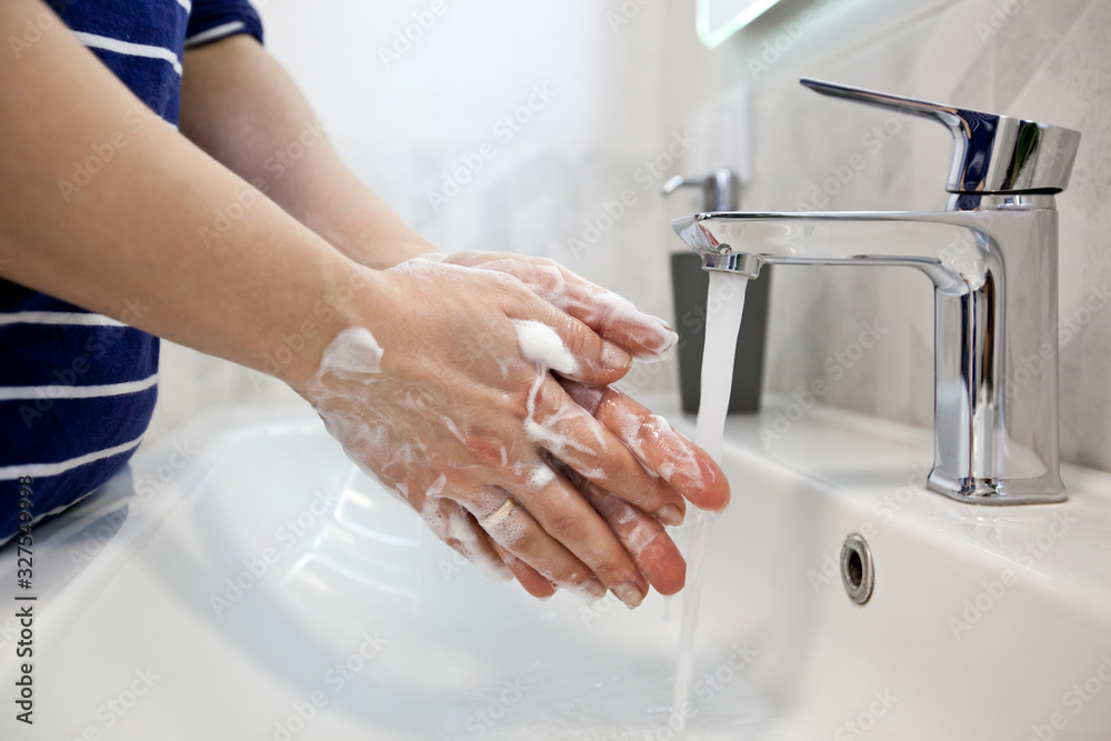 The woman is washing hands with soap in the bathroom The woman is washing hands with soap in the bathroom