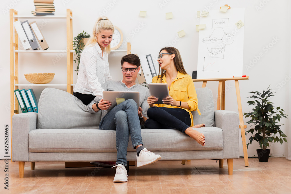 Business colleagues sitting on sofa and working on laptop