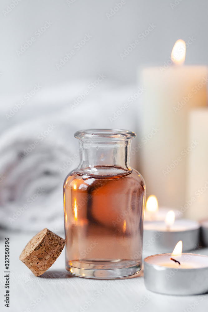 Concept of spa treatment in salon. Natural organic oil, towel, candles as decor. Atmosphere of relax, serenity and pleasure. Anti-stress and detox procedure. Luxury lifestyle. White wooden background Concept of spa treatment in salon. Natural organic oil, towel, candles as decor. Atmosphere of relax, serenity and pleasure. Anti-stress and detox procedure. Luxury lifestyle. White wooden background