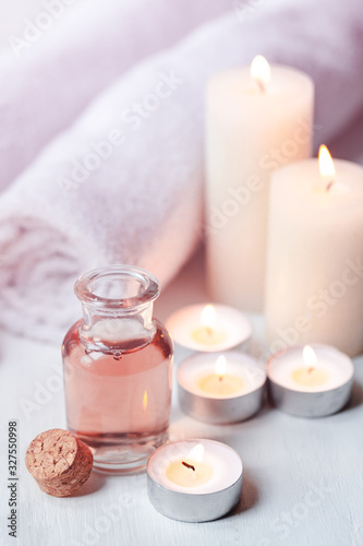 Concept of spa treatment in salon. Natural organic oil  towel  candles as decor. Atmosphere of relax  serenity and pleasure. Anti-stress and detox procedure. Luxury lifestyle. White wooden background