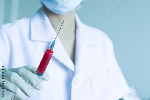 Syringe injection in doctor's hand .Corona virus spreading in wuhan China.Nurse wearing respirator mask Medical blood and vaccine chemistry research.Hospital equipment and Healthcare concept