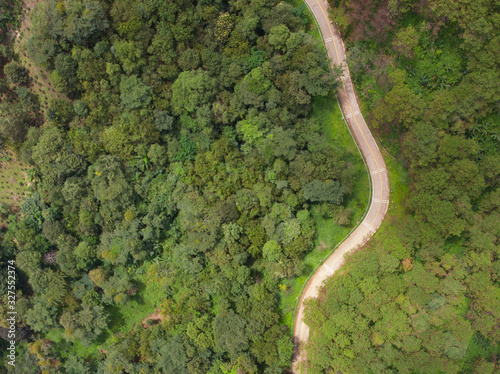 Aerial view of winding road with pine tree forest in mountain.Scenery Bird eye view of asphalt road landscape.High view from drone save drive transport and journey in countryside concept
