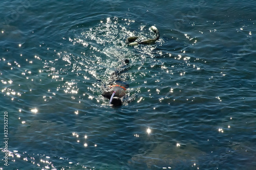 A man collects oysters at the bottom of the sea in a rubber suit with a mask and a special net for folding.