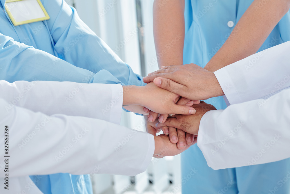 Close-up image of doctors and nurses stacking hands and expressing support Close-up image of doctors and nurses stacking hands and expressing support