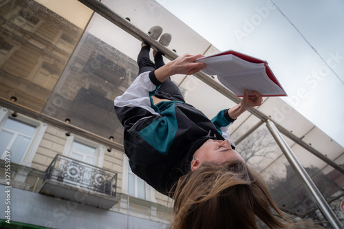 Photos Girl hanging by feet upside down in the street and reading book