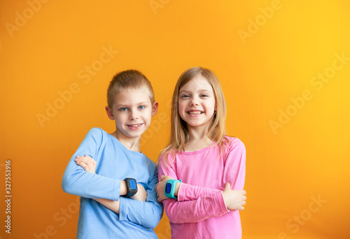 Happy children 6-8 years old with a smart GPS watch talking to parents safely. orange background