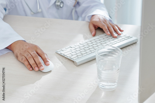 Φωτογραφία Close-up image of general practitioner working on computer at his office desk