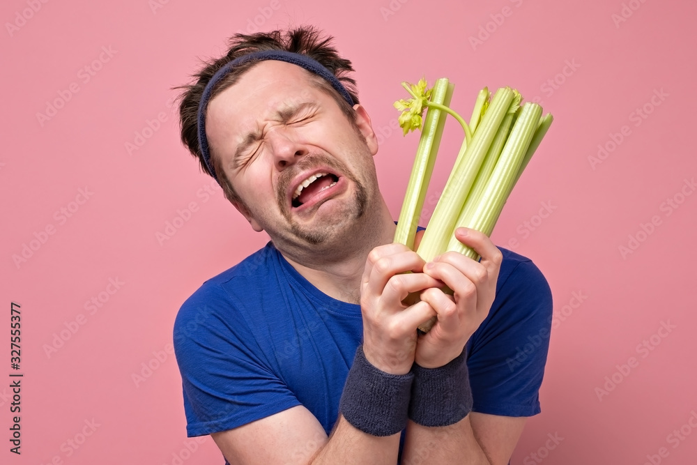 man holding celery crying. I hate vegetables but should eat for healthy